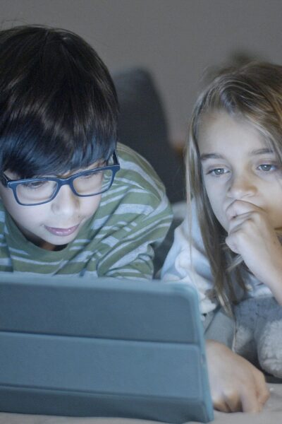 a young boy wearing glasses and a young girl watching a tablet screen together with safe parental controls