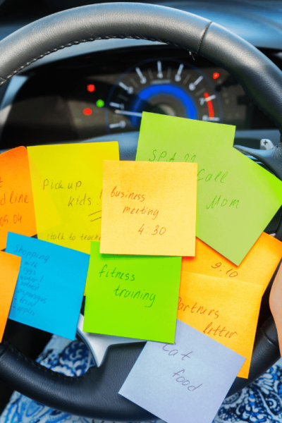 an overwhelmed mom with ADHD driving with several sticky notes on her steering wheel to remind her of her many tasks