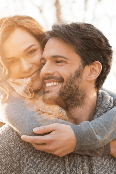 woman with her arms around a man's neck while they are both smiling