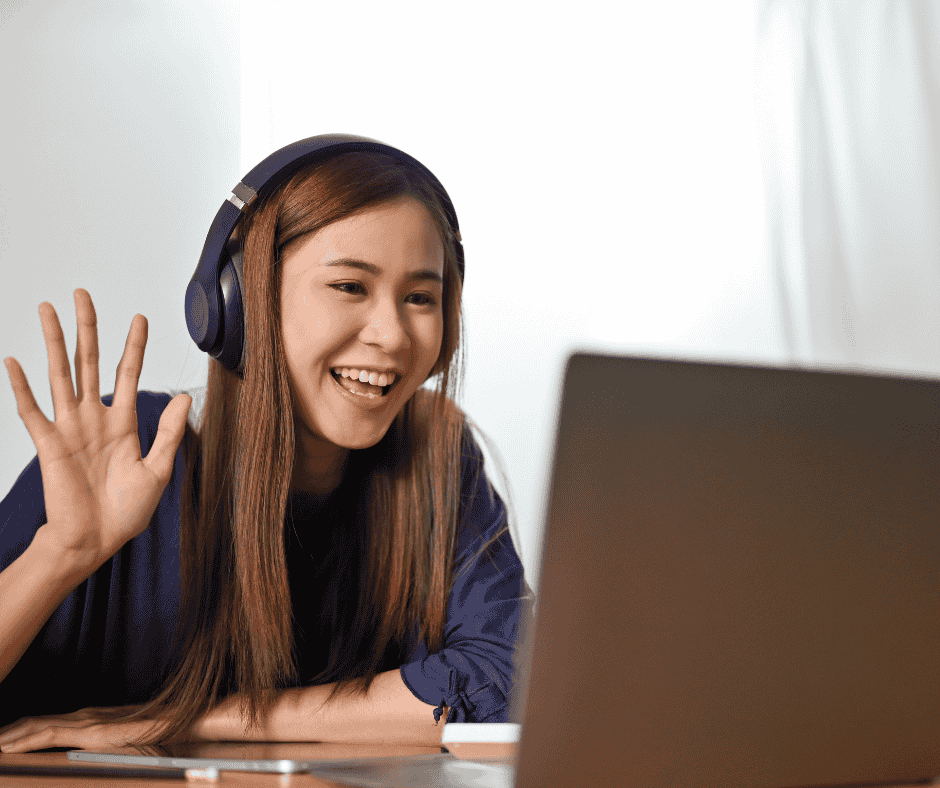 mom using online tutoring as her side hustles. woman waving at people on computer screen while wearing headphones