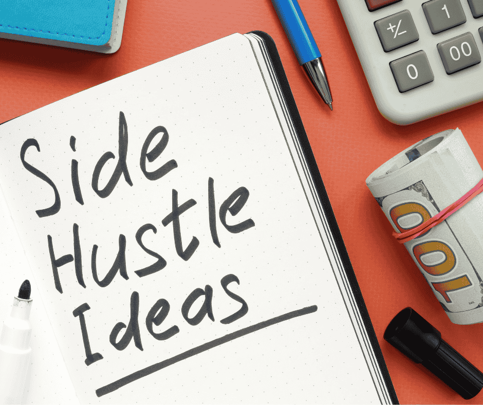 the words side hustle ideas written in black marker on a notebook lying on a desk. There is also rolled up cash, a pen, and a calculator