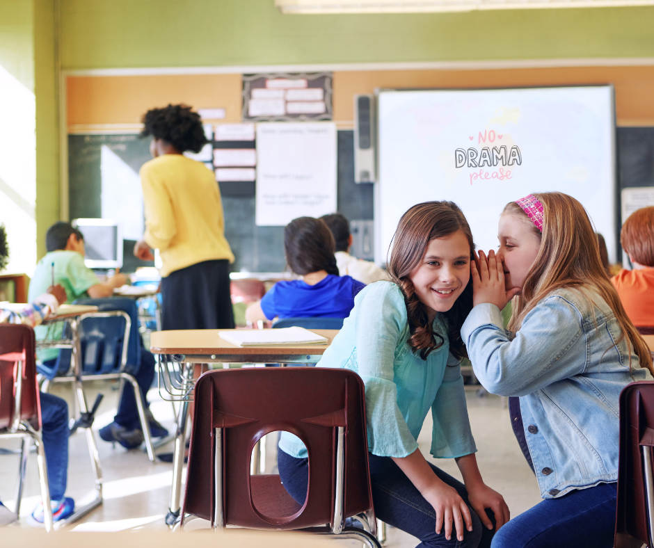 girl bullies in middle school whispering in each other's ear during class